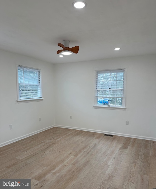 empty room featuring wood finished floors, baseboards, and a wealth of natural light