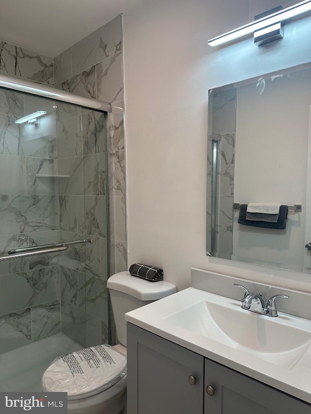 full bathroom with a marble finish shower, toilet, and vanity