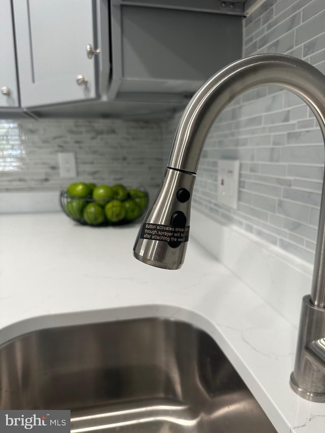 room details featuring tasteful backsplash, light stone countertops, and a sink