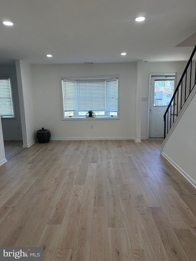 unfurnished living room with stairway, recessed lighting, wood finished floors, and baseboards