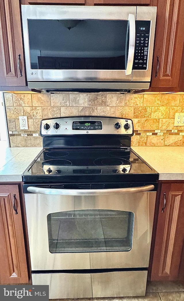 details featuring stainless steel appliances, backsplash, brown cabinetry, and light countertops