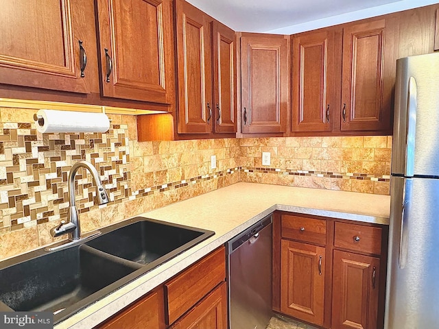 kitchen featuring brown cabinetry, a sink, light countertops, appliances with stainless steel finishes, and backsplash