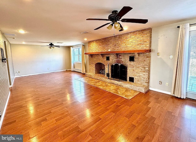 unfurnished living room featuring visible vents, wood finished floors, a fireplace, baseboards, and ceiling fan