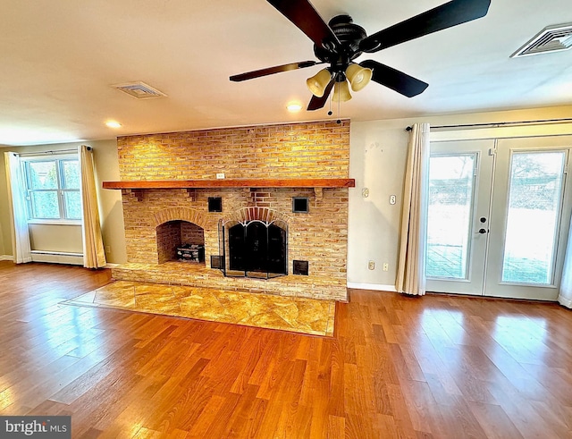 unfurnished living room with wood finished floors, visible vents, a baseboard radiator, a fireplace, and french doors