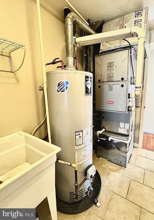 utility room with heating unit, water heater, and a sink