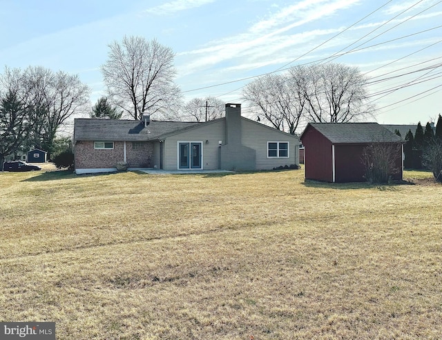 back of property featuring a chimney, a storage shed, a yard, an outdoor structure, and a patio