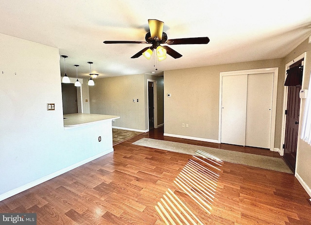 unfurnished living room featuring ceiling fan, baseboards, and wood finished floors