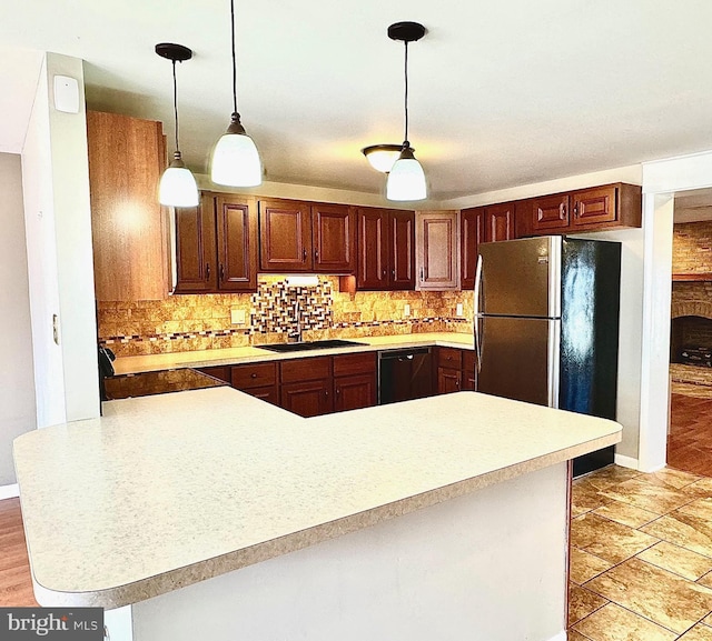 kitchen featuring freestanding refrigerator, a sink, light countertops, black dishwasher, and backsplash