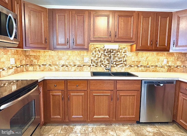 kitchen with decorative backsplash, light countertops, appliances with stainless steel finishes, and a sink