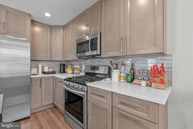 kitchen with backsplash, stainless steel appliances, light countertops, and light wood-style floors