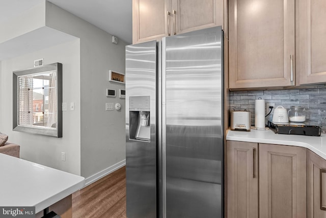 kitchen with wood finished floors, baseboards, light countertops, stainless steel refrigerator with ice dispenser, and tasteful backsplash