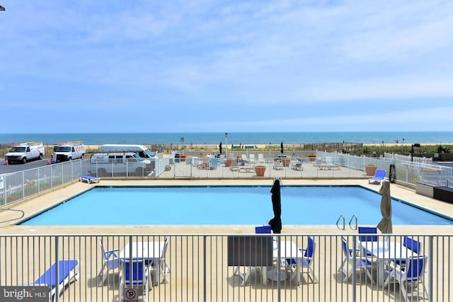 community pool featuring a water view and fence