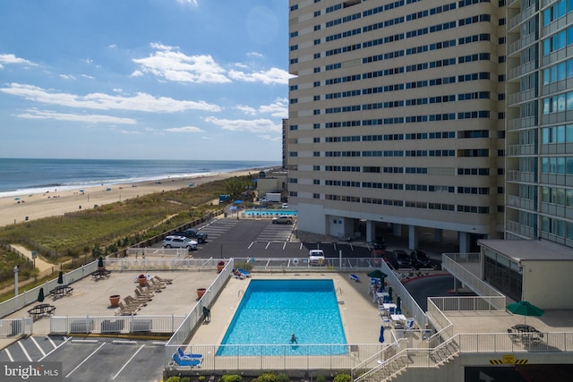 pool with a beach view, a water view, and fence