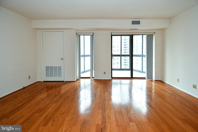 spare room with visible vents, baseboards, and wood finished floors