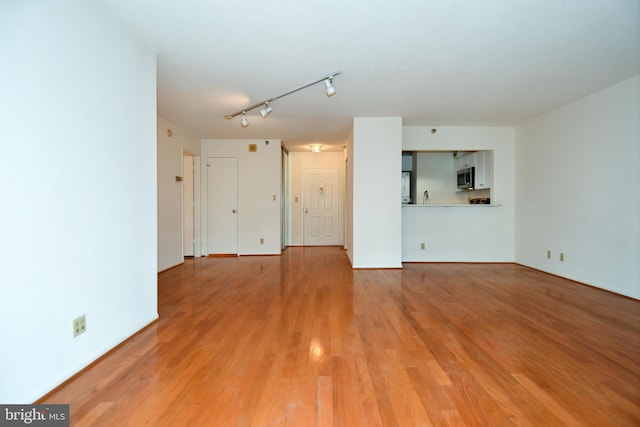 unfurnished living room with track lighting and light wood-style flooring