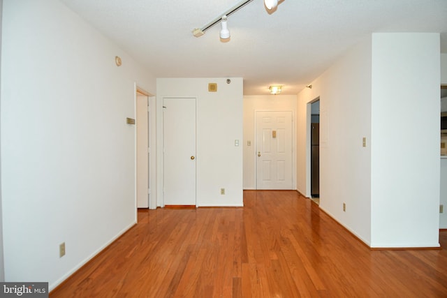 unfurnished room featuring track lighting, baseboards, and wood finished floors