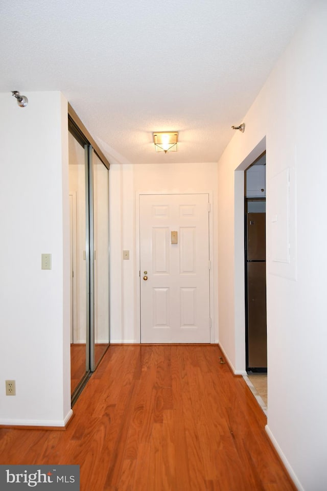 hallway featuring baseboards and light wood-style flooring