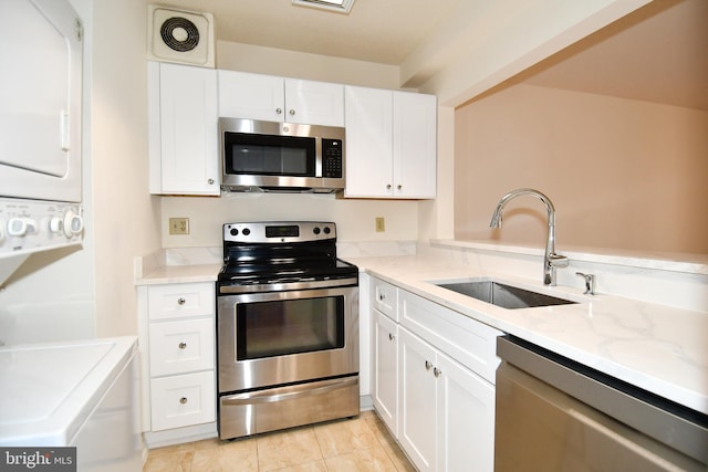 kitchen with stacked washer / dryer, visible vents, stainless steel appliances, white cabinetry, and a sink