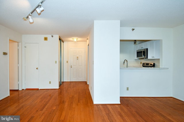 interior space with baseboards, wood finished floors, and track lighting