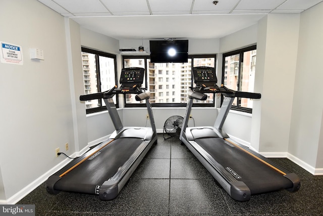 exercise area with a paneled ceiling and baseboards