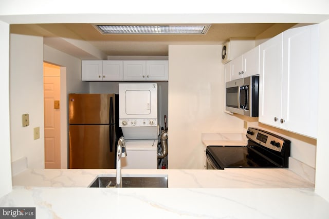 kitchen with white cabinets, visible vents, stacked washer / drying machine, and appliances with stainless steel finishes