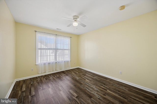 empty room with dark wood finished floors, visible vents, ceiling fan, and baseboards