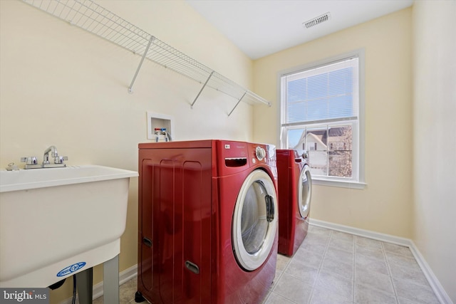 washroom featuring visible vents, baseboards, laundry area, washer and dryer, and a sink