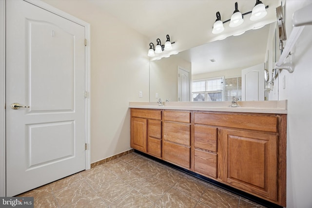 bathroom featuring a sink, walk in shower, baseboards, and double vanity