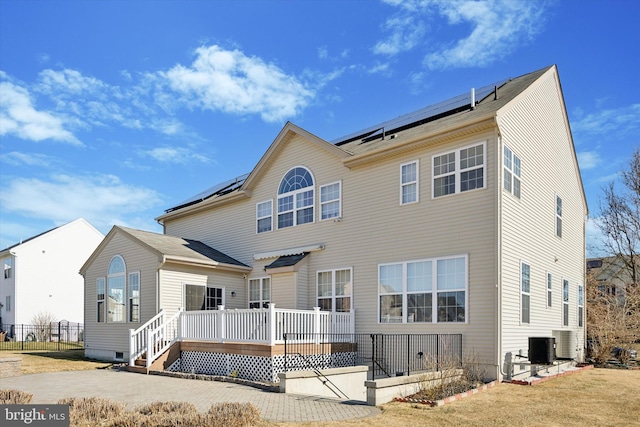 back of house featuring a deck, central air condition unit, and roof mounted solar panels