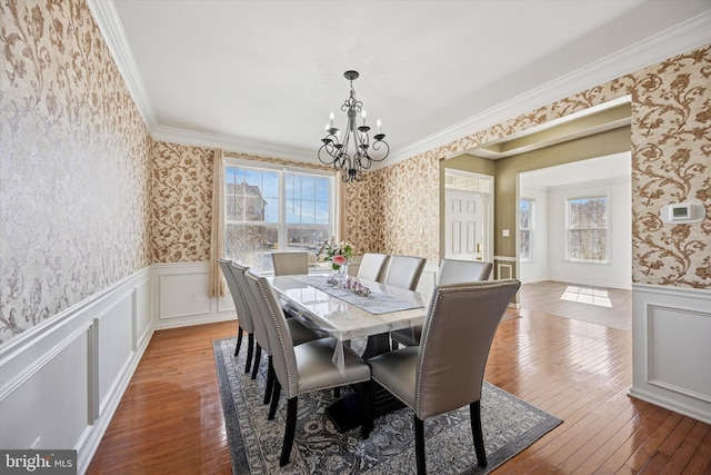 dining area with a wainscoted wall, wallpapered walls, crown molding, and hardwood / wood-style floors