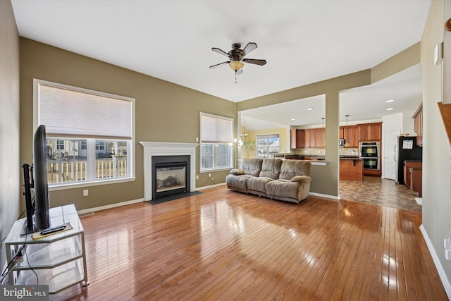 living room with baseboards, a fireplace with flush hearth, hardwood / wood-style floors, recessed lighting, and a ceiling fan