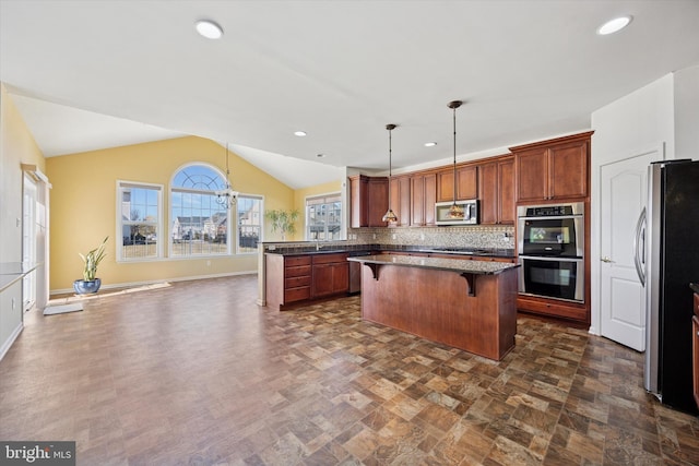 kitchen featuring a center island, pendant lighting, a breakfast bar, vaulted ceiling, and stainless steel appliances