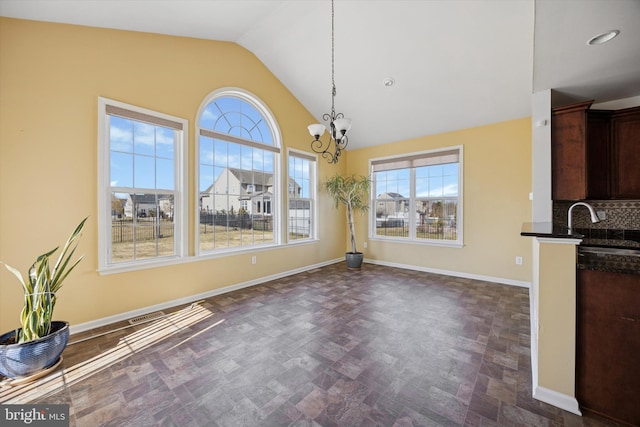 unfurnished dining area with a sink, baseboards, plenty of natural light, and vaulted ceiling