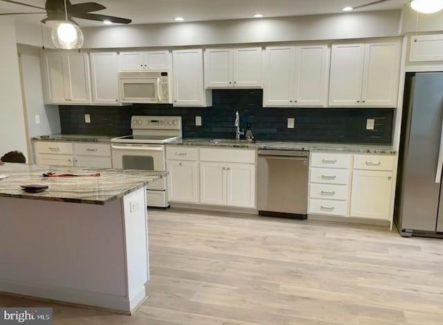 kitchen featuring a ceiling fan, light stone countertops, a sink, stainless steel appliances, and light wood-type flooring