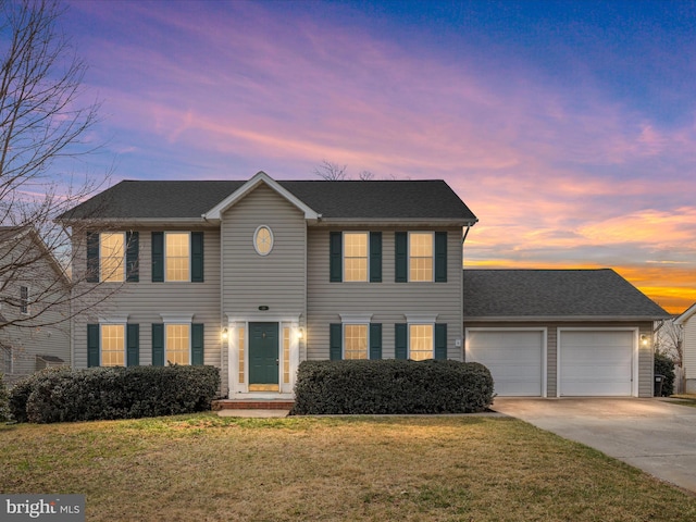 colonial house with driveway, a front yard, a garage, and a shingled roof