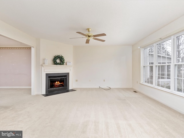 unfurnished living room with a ceiling fan, a fireplace with flush hearth, carpet, and baseboards