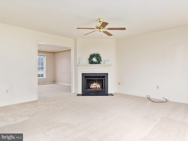 unfurnished living room with baseboards, carpet floors, a ceiling fan, and a fireplace with flush hearth