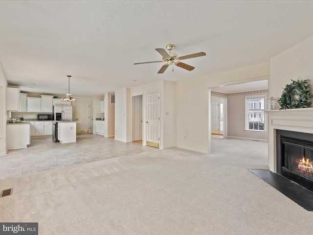 unfurnished living room featuring a fireplace with flush hearth, light colored carpet, baseboards, and ceiling fan