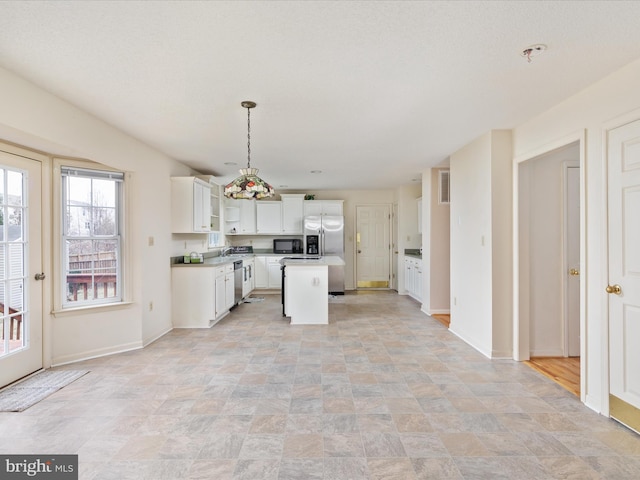 kitchen with baseboards, a kitchen island, white cabinets, and light countertops