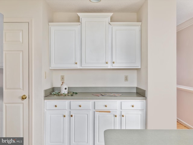 kitchen with light countertops, white cabinets, baseboards, and a textured ceiling