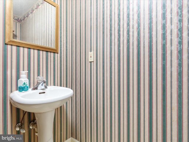 bathroom featuring a sink and wallpapered walls