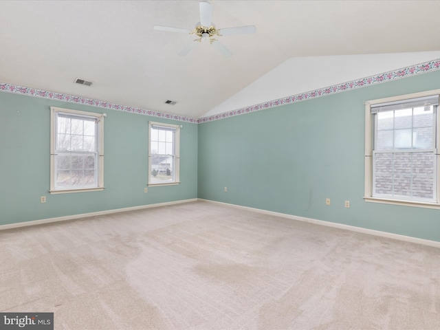 carpeted empty room with lofted ceiling, baseboards, visible vents, and ceiling fan