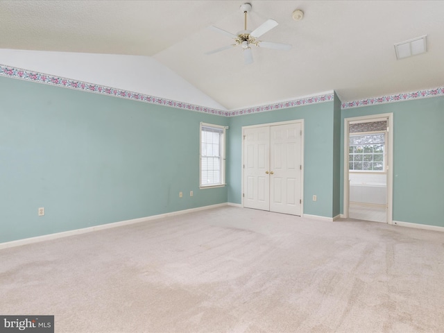 unfurnished bedroom featuring lofted ceiling, multiple windows, visible vents, and carpet floors