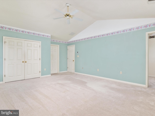 unfurnished bedroom with two closets, baseboards, carpet flooring, high vaulted ceiling, and a ceiling fan