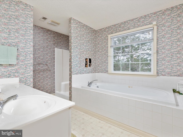 full bathroom featuring a sink, a textured ceiling, wallpapered walls, double vanity, and a bath