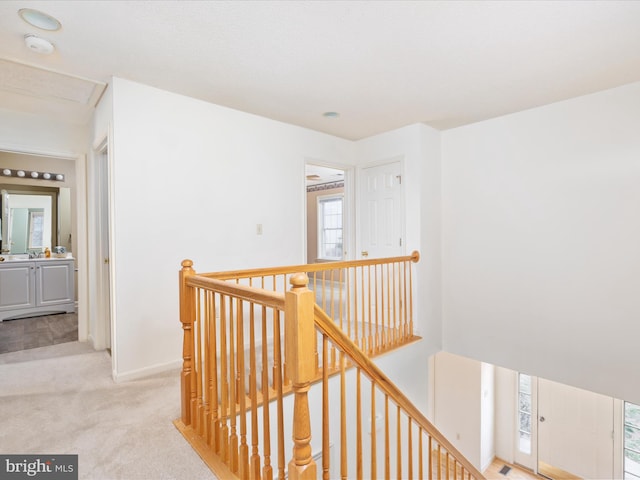 corridor featuring an upstairs landing and light colored carpet