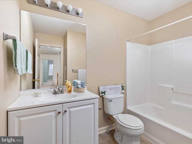 bathroom with toilet, a textured ceiling, baseboards, bathing tub / shower combination, and vanity