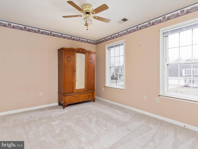 spare room featuring visible vents, baseboards, light colored carpet, and a ceiling fan