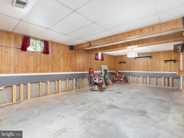 interior space with visible vents, a paneled ceiling, and wooden walls