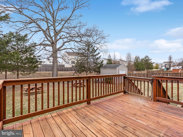 wooden terrace featuring a fenced backyard, a garage, an outdoor structure, and a shed